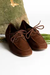 Mocasín de cuero marrón con cordones, diseño de puntera cuadrada y costuras visibles.