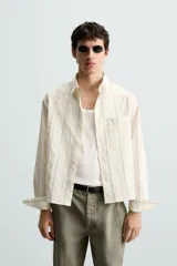 Camisa relaxed fit de manga larga con cuello solapa, confeccionada en tejido con mezcla de algodón. Presenta un estampado de rayas verticales en tonos beige, blanco y marrón. Incluye un bolsillo plastrón en el pecho, puños con botón y aberturas laterales en el bajo. Cierre frontal de botonadura.