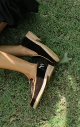 Mocasines de diseño clásico en terciopelo azul marino con ribete tostado y aplique metálico de caballo en el lateral del talón.