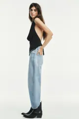 Pantalón de jean celeste claro, corte cropped, tiro medio, con trabillas y cinco bolsillos. Cierre frontal con cremallera y botón metálico.