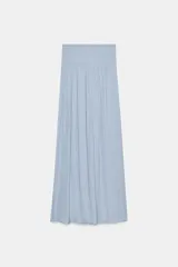 Falda larga color crudo, de tiro alto con cintura elástica tipo nido de abeja y cordón ajustable.