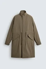 Parka relaxed fit de tejido técnico ligero, color verde militar, con cuello subido, manga larga y bolsillos de plastrón con solapa en la cadera. Cuenta con cintura ajustable con cordones y cierre frontal con cremallera oculta por solapa con botones a presión.