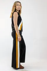 Pantalón negro de corte palazzo con rayas laterales blancas y mostaza.