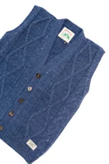 Chaleco azul de punto con diseño de trenzas y rombos, con cuello en V y cierre frontal con botones marrones.