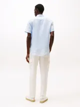 Camisa celeste de lino con corte regular, manga corta, cuello abotonado y logo de Tommy Hilfiger bordado en el pecho.