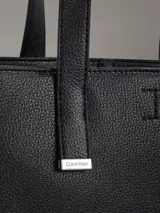 Cartera tipo tote de cuero sintético color negro, con doble asa corta y correa larga desmontable.