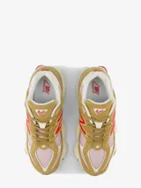 Zapatillas urbanas New Balance modelo 9060, color beige con detalles en rosa y rojo. Confeccionadas en gamuza y malla, con logo "N" característico en los laterales y entresuela con tecnología ABZORB y SBS.