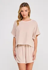 Blusa corta de lino y viscosa color beige, con escote redondo, mangas cortas holgadas tipo mariposa y detalles de bordado festoneado en contrastes blancos en el cuello, puños y ruedo.