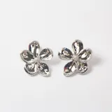 Par de caravanas con diseño de flor de cinco pétalos en acabado metálico plateado brillante.