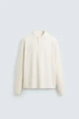 Polo de punto de manga larga con cuello solapa y cierre frontal de botones. Presenta un diseño de corte regular con aberturas laterales en el bajo.