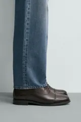 Zapato de vestir tipo oxford con puntera reforzada, confeccionado en piel de color marrón oscuro. Presenta cierre mediante cordones al tono, forro interior y plantilla de piel, y suela a contraste con tacón bajo.