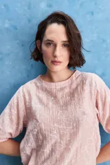 Blusa de manga corta color rosado con estampa orgánica de inspiración floral, cuello redondo y ajuste mediante lazo en el ruedo.