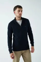 Sweater gris de punto con cuello alto y medio cierre con cremallera.