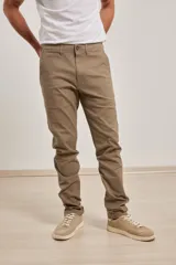 Pantalón de vestir verde oliva, de corte slim fit, sin pinzas, con bolsillos laterales y traseros. Se ajusta a la cintura con cinturón de cuero marrón.