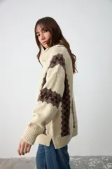 Sweater de punto grueso con cuello tortuga, diseño de rayas verticales en color crudo y marrón, de corte holgado y manga larga.