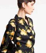 Vestido midi de tejido satinado negro con estampado floral amarillo, cuello solapa, manga larga, abotonado delantero y cruzado lateral.