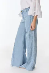 Pantalón de pierna ancha con acabado brillante, confeccionado en lino. Presenta un diseño de tiro medio con cierre de botón y cremallera, bolsillos traseros y etiqueta de marca en la cintura.