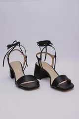 Sandalias negras de cuero con tacón cuadrado y tiras finas para atar al tobillo.