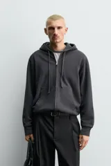Sudadera de corte relajado confeccionada en tejido compacto de algodón con interior forrado, cuello con capucha, manga larga, bolsillos frontales tipo canguro y acabados en rib.