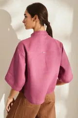 Camisa de lino color fucsia, con cuello mao, mangas cortas holgadas y cierre frontal con botones de madera. Cuenta con bolsillos frontales en el pecho.