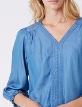 Blusa Zac & Rachel de lyocell color azul, con escote en V y panel central con pespuntes. Presenta mangas tres cuartos abullonadas con frunces en los hombros y puños elastizados con detalle de volante.