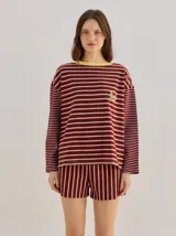 Remera manga larga de corte oversize y cuello redondo, con diseño a rayas horizontales en tonos claros y verde militar, y detalle de bordado frontal.