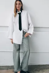 Camisa oversize de algodón con cuello redondo y solapa, manga larga con puño con vuelta y hombro caído. Presenta detalle de tablas en el delantero, cierre frontal con botones ocultos y corbata a contraste incluida.