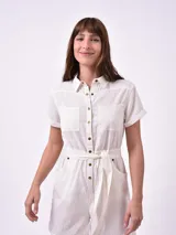 Mono corto color blanco con cuello camisero, cierre frontal con botones, cinturón de lazo y bolsillos laterales.