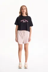 Remera cropped de algodón color negro con diseño gráfico estampado en el frente con las inscripciones 'One day in', 'NEW YORK' y 'EST. 69'. Presenta mangas cortas y calce cómodo.