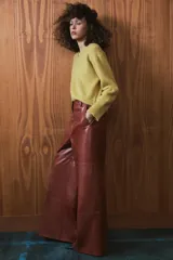 Pantalón de tiro medio confeccionado en 100% piel, con diseño de pierna ancha, cintura con trabillas, bolsillos laterales y cierre frontal con cremallera, botón y ganchos metálicos.