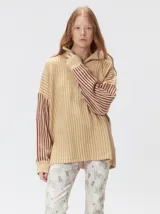 Pullover de tejido acanalado grueso con diseño bicolor en tonos marrón y bordó. Presenta cuello alto con cierre frontal, mangas largas y corte holgado.