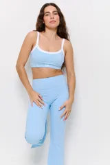 Conjunto deportivo compuesto por un top corto con cuello redondo y ribete blanco, y un pantalón largo de tiro alto con corte acampanado en el bajo.
