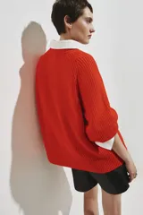 Top de punto acanalado color naranja, con cuello redondo, mangas al codo de corte raglán y diseño oversized. Presenta terminaciones acanaladas en cuello, puños y bajo.