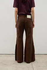 Pantalón de denim tiro alto con corte oxford y tajos laterales en el ruedo. Presenta cierre frontal con botones a la vista y costuras verticales decorativas.