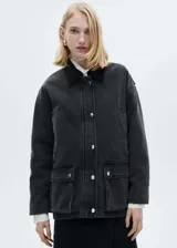 Chaqueta estilo vaquero de algodón en color negro lavado, con diseño oversize y acolchado interior. Presenta cuello camisero en contraste, cierre frontal con botones a presión, dos bolsillos de parche con solapa y dos bolsillos de ribete en la parte delantera.