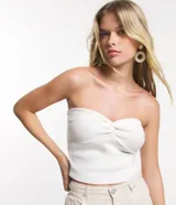 Top cropped de punto color blanco, sin breteles y con detalle retorcido en el busto.