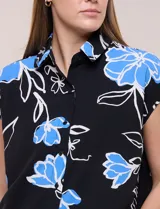 Túnica de gasa negra con estampado floral en tonos azules y blancos, cuello camisero, manga corta y cierre frontal de botones.