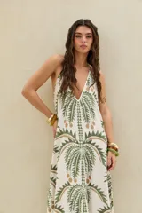 Vestido largo de diseño halter, color crudo con gran estampado de palmeras en tonos verdes y marrones.