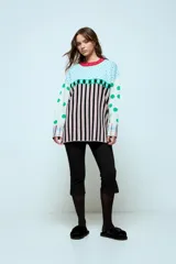 Sweater de punto con diseño geométrico y a rayas, de corte holgado y manga larga. Presenta un patrón combinado de lunares en las mangas, rombos en la parte superior y rayas verticales en el cuerpo.