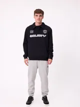 Babucha jogger color gris oscuro, con cintura elástica ajustable con cordón, bolsillos laterales y puños elásticos en los tobillos. Presenta un logo estampado en el muslo izquierdo.