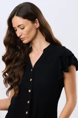 Camisa de lino y viscosa color beige, con cuello mao, escote en V y botones frontales de madera. Presenta mangas cortas con volados delicados.