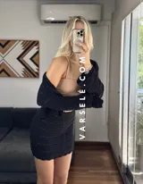 Conjunto de dos piezas tejido al crochet color crudo. Incluye una mini falda de tiro alto y un cardigan corto con mangas largas y lazos para atar en el frente.