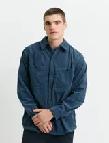 Sobrecamisa de pana color marrón, con manga larga, cierre frontal con botones y dos bolsillos frontales con solapa y botón.