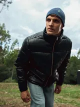 Campera puffer negra de cuero sintético con cierre frontal y cuello alto.