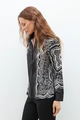 Camisa negra con estampado de arabescos en blanco y gris, de manga larga y corte clásico.