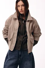 Campera corta color marrón, con cuello alto estructurado, cierre frontal y bolsillos delanteros con solapa. Presenta puños y cuello en tejido acanalado, con un diseño de corte recto y minimalista.