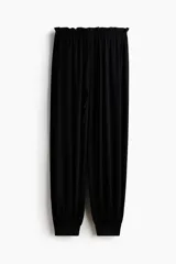 Pantalón globo negro de punto de crepé, con corte relajado, cintura elástica de tiro bajo con cordón ajustable y puños anchos en las piernas.