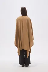 Poncho abierto de corte asimétrico y holgado, confeccionado en tejido de punto suave color beige, con mangas amplias y caída fluida.