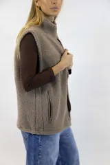 Chaleco de corderito color rosado, con cuello alto, cierre frontal y un bolsillo con cierre en el pecho.