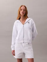 Buzo con capucha y cierre frontal de cremallera, confeccionado en mezcla de algodón y poliéster. Presenta corte regular cropped, mangas largas y logo de la marca estampado en el pecho.